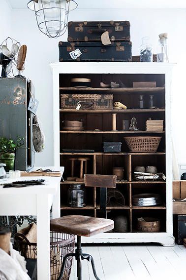 A curated office wall with a mix of ornate gilded mirrors, minimalist sketches, and a cream-colored macramé hanging above a white-painted brick wall.