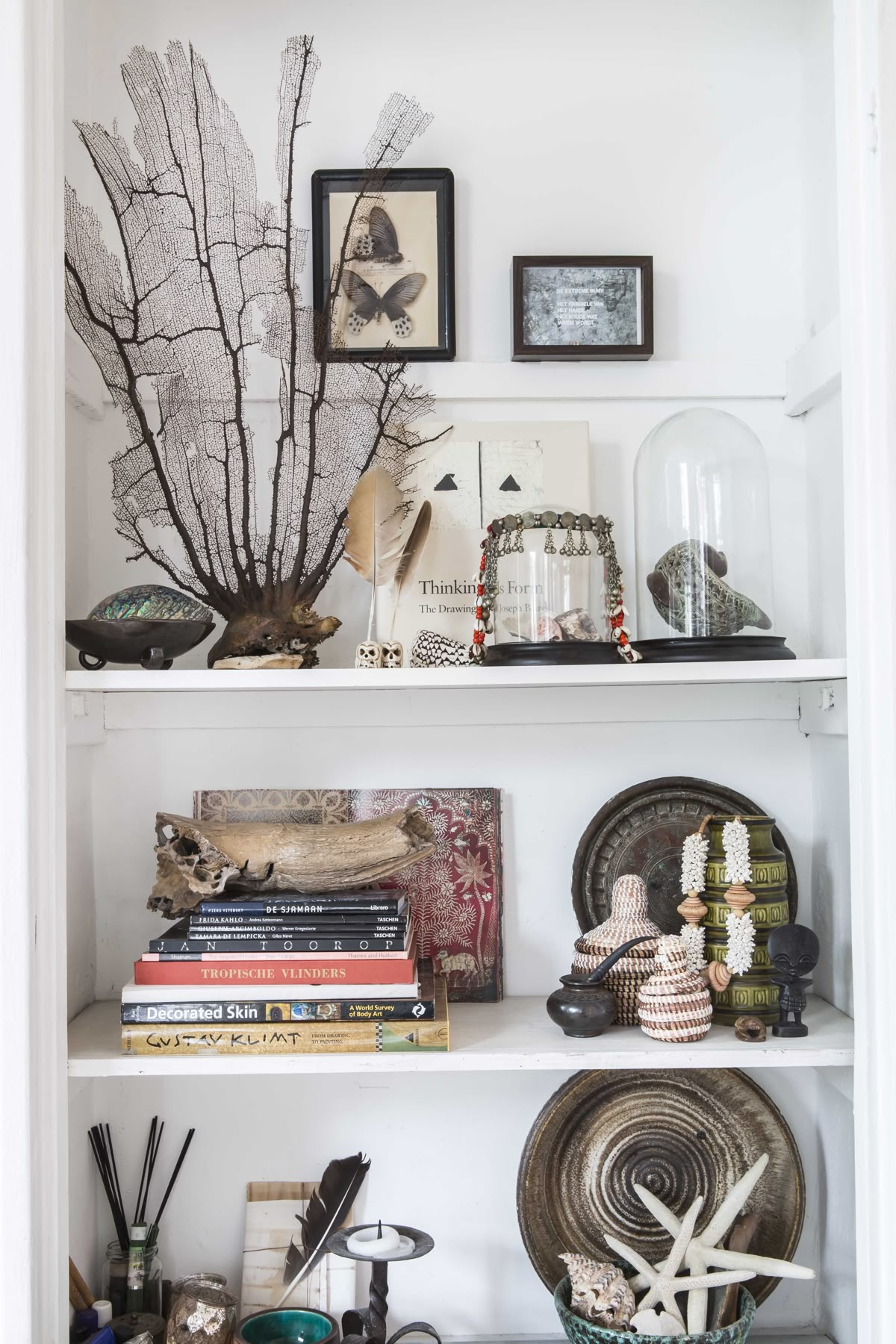 A set of tall, olive green vintage metal lockers standing in a minimalist bedroom, providing a rugged industrial contrast to a soft linen-clad bed and a plush sheepskin rug.