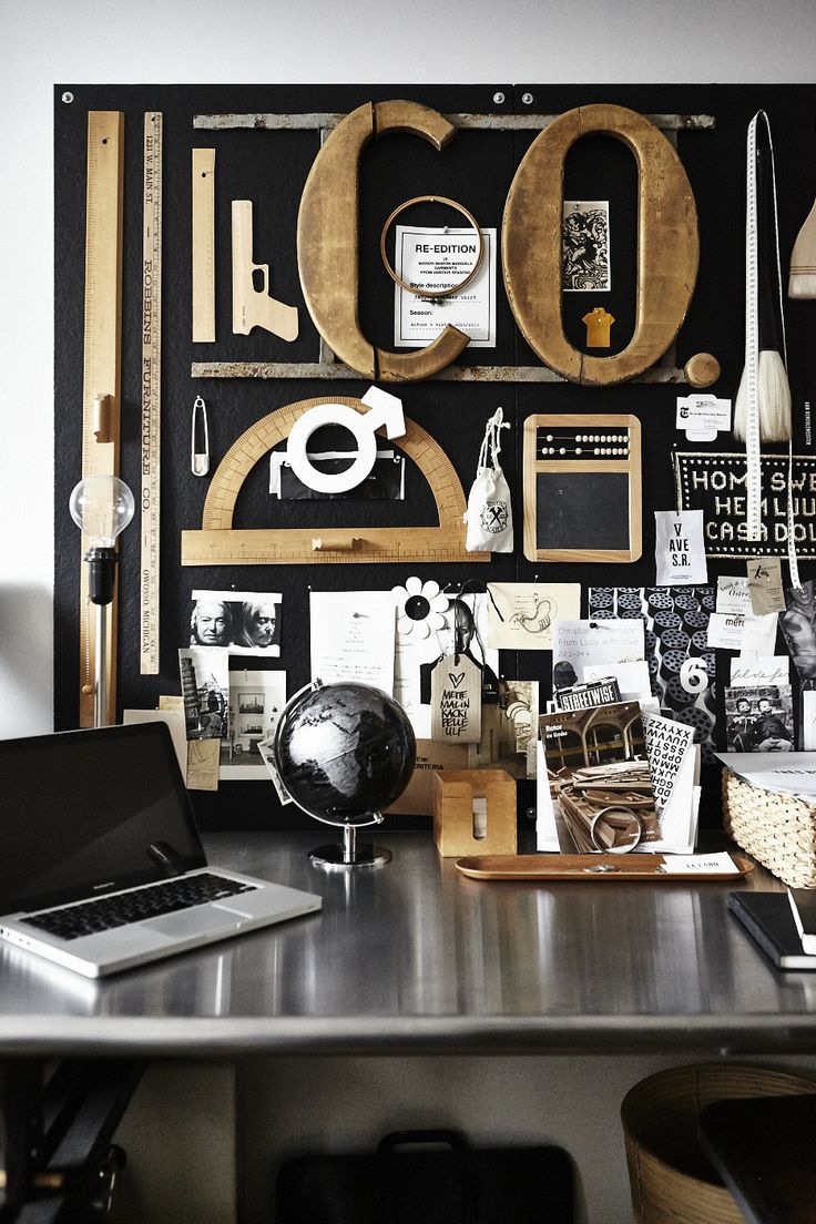 A modern executive workspace featuring a honed white marble desk on a slender black steel frame, paired with a black leather designer chair and a large abstract painting on the wall.