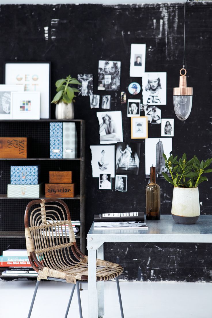 A minimalist office corner featuring a slim, arched matte black floor lamp and a singular, oversized architectural photograph leaning against a crisp white wall.