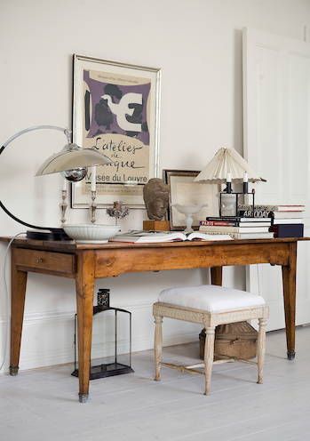 Close-up of an organized desktop with deep black accents, including a ceramic pencil cup, a minimalist black clock, and a textured black vase holding a single green branch.