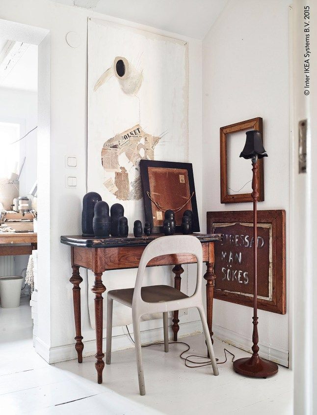 A curated gallery wall above a small workspace, showing a mix of abstract art and botanical prints in various black and gilded frames, creating an eclectic and sophisticated backdrop.