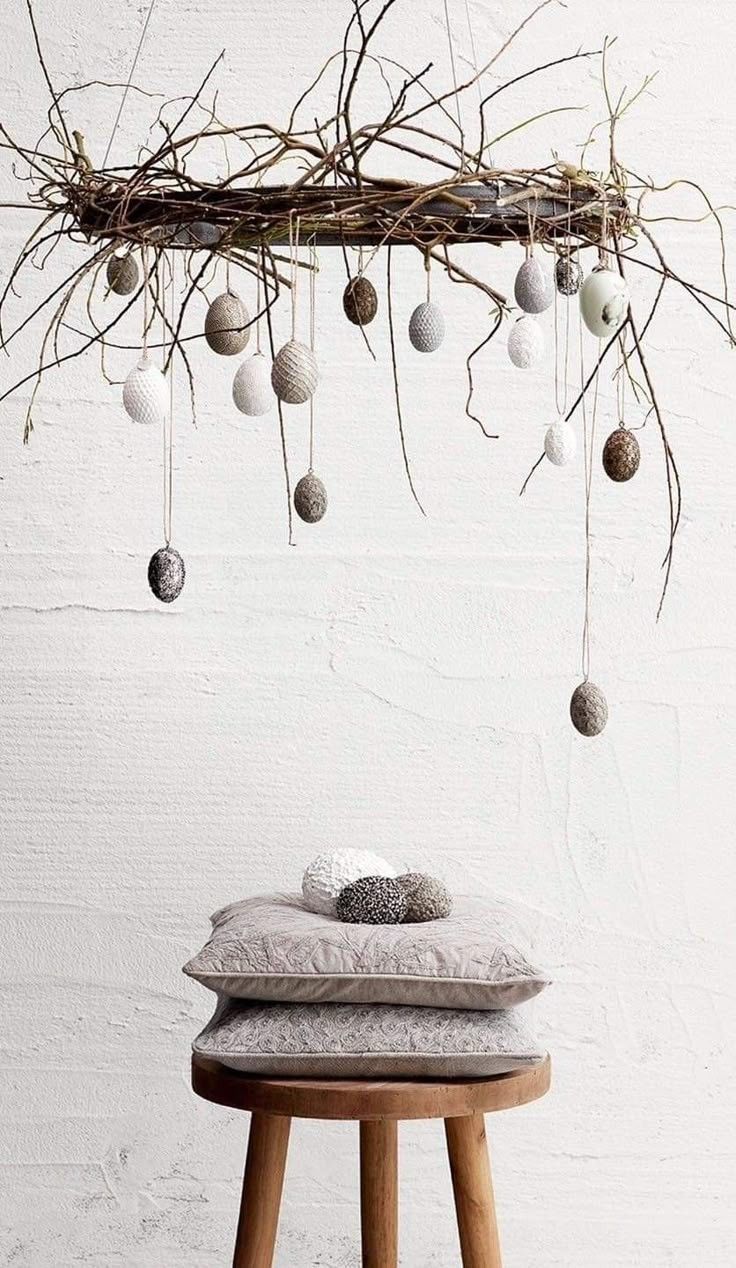 A rustic, European-style Easter display with wild pussy willow branches in a vintage stoneware crock. The branches are decorated with real, hand-blown eggshells in natural shades of cream and speckled brown, surrounded by a few moody hellebore blooms at the base.